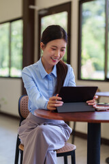 Asian businesswoman using tablet computer working online at cafe restaurant browsing internet smiling happy professional freelancer entrepreneur digital nomad © Pichsakul