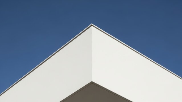 Minimalist corner of a white building against a clear blue sky.