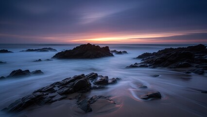 Obraz premium Ethereal seascape at dusk with smooth water and coastal rocks.
