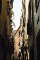 Fototapeta premium Narrow old town street with rustic apartment balconies and laundry hanging in Barcelona