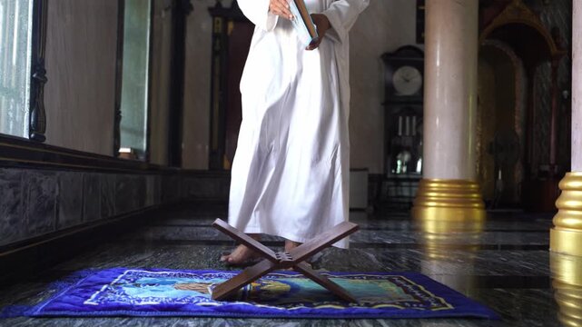 Muslim young man sitting in Tashahhud position during Salah prayer inside mosque.