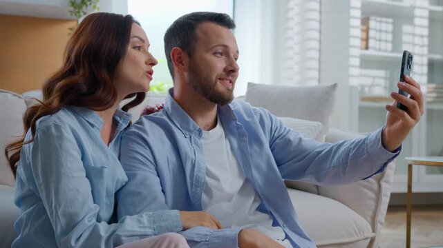 Joyful carefree Caucasian couple talking video call with mobile phone family waving hello showing thumb up communicate conference with smartphone application family man with woman happy chat at home
