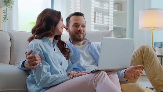 Cheerful Caucasian family talking video call with laptop happy smiling communicating virtual chat at home carefree couple man with woman talk computer conference webcam chatting joyful in living room