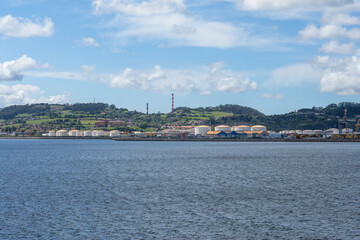 Fototapeta premium Industrial harbor landscape in Gijon, Northern Spain, showing cargo port facilities, fuel reservoirs, and coastal scenery
