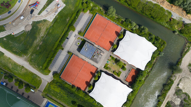 Aerial view of H.C. Rijnvliet sports complex featuring red courts, a parking lot, and a canal surrounded by green trees in Utrecht, Utrecht, Netherlands.