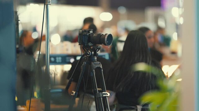 Camera setup at a busy event with people in the background enjoying drinks and conversation