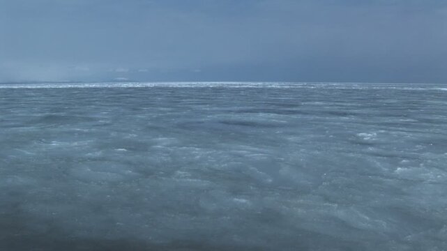 シャーベット状の氷に覆われた海と流れ着く流氷のうねり