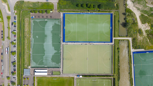Aerial view of H.C. Rijnvliet hockey fields featuring green and blue artificial turf pitches, a parking lot, and surrounding greenery in Utrecht, Utrecht, Netherlands.