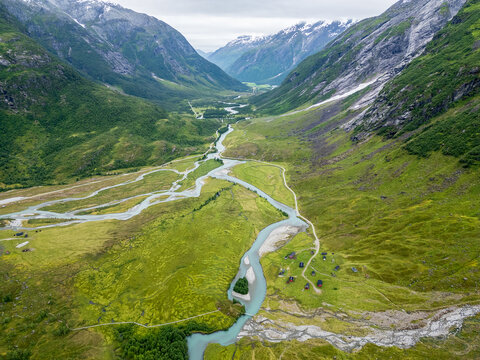 Aerial drone views of the tundra landscape in Jostedalsbreen National Park, where glacial rivers carve braided channels through a wide alpine valley in western Norway. The images capture the raw wilde