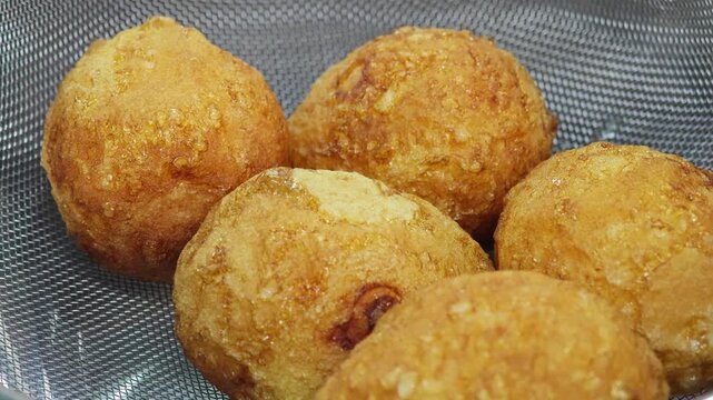 Macro shot of fried hard-boiled eggs in a strainer.