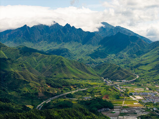Fototapeta premium A scenic view shows the green mountains of Wuyi Mountain in Fujian China with a highway winding through the valley below