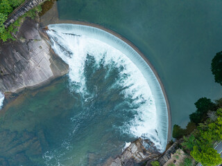 Aerial view of a curved dam creating a scenic waterfall on the river in Wuyi Mountain located in Fujian China © AS_SleepingPanda