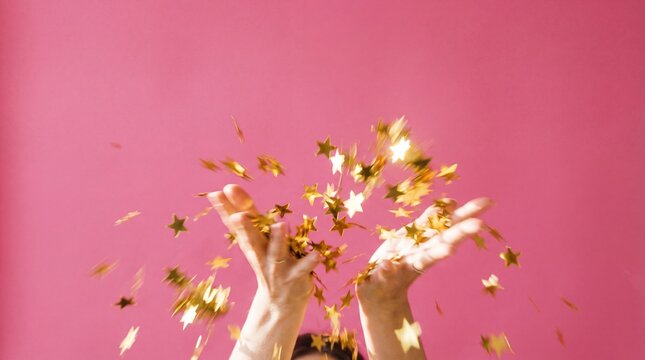 caucasian hands throwing golden star confetti on pink background. joyful celebration, winning and success concept. festive party decoration. banner, website header with copyspace.