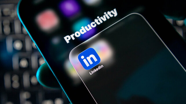 Closeup of a smartphone screen displaying the linkedin app icon within a productivity folder