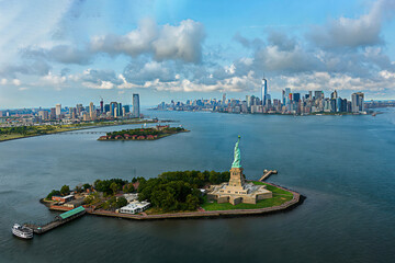 Aerial view of the Statue of Liberty with Lower Manhattan skyline and dramatic clouds over New York Harbor. © VisualCoordinates