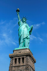 Fototapeta premium Low angle view of the Statue of Liberty in New York City with clear blue sky and dramatic perspective.