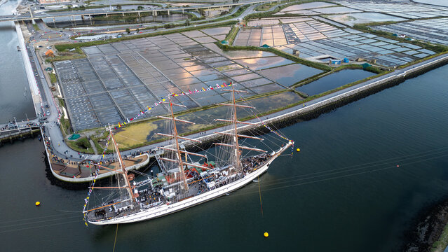 Aerial view of the tall ship NRP Sagres decorated with signal flags navigating the Canal de Aveiro near the salt pans Aveiro, Aveiro, Portugal.