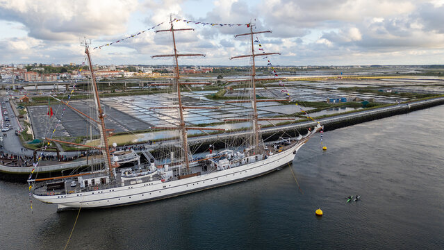 Aerial view of the tall ship NRP Sagres decorated with signal flags navigating the Canal de Aveiro near the salt pans Aveiro, Aveiro, Portugal.