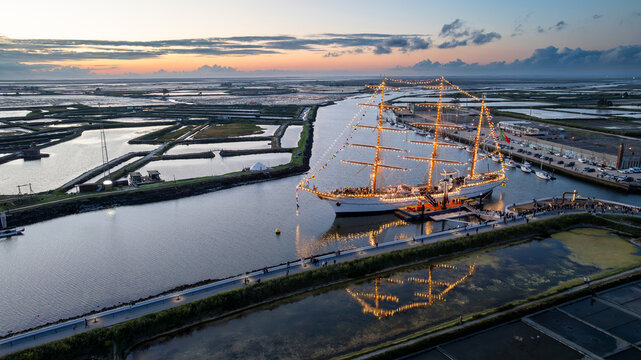 Aerial view of the tall ship NRP Sagres decorated with signal flags navigating the Canal de Aveiro near the salt pans Aveiro, Aveiro, Portugal.