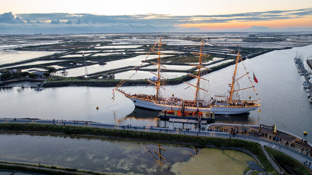 Aerial view of the tall ship NRP Sagres decorated with signal flags navigating the Canal de Aveiro near the salt pans Aveiro, Aveiro, Portugal.