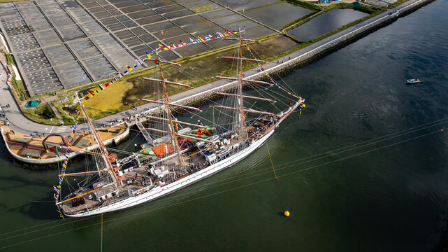 Aerial view of the tall ship NRP Sagres decorated with signal flags navigating the Canal de Aveiro near the salt pans Aveiro, Aveiro, Portugal.
