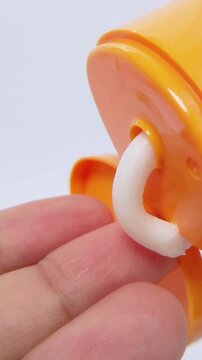 Pouring white cream onto fingertip from orange beauty product. UV skincare and self care concept in close up.