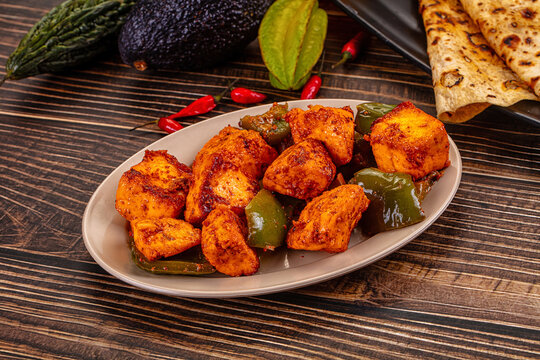 Indian Paneer Tikka Masala inl with Roti bread on a dark wooden table