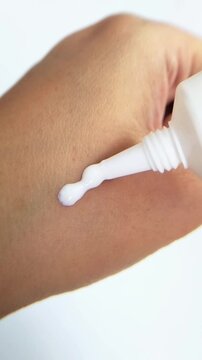 Pouring white cream onto skin. Skincare and beauty concept isolated on white background in close up view.