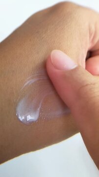 Applying white cream evenly onto hand skin. Skincare and self care concept in close up vertical view.