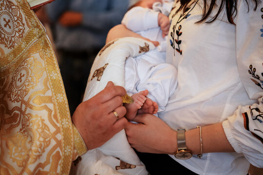 Priest anointing baby foot during Orthodox baptism