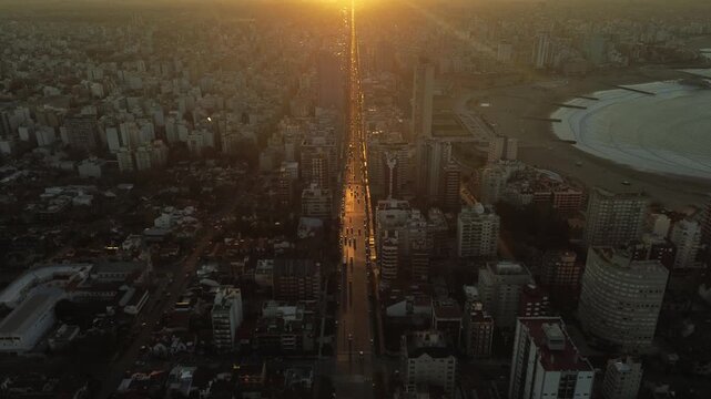 Drone aerial footage of golden hour sunset over Col&oacute;n Avenue and the coastline of Mar del Plata, Argentina, with Torre&oacute;n del Monje and Atlantic Ocean during winter. Urban coastal cityscape in South Am