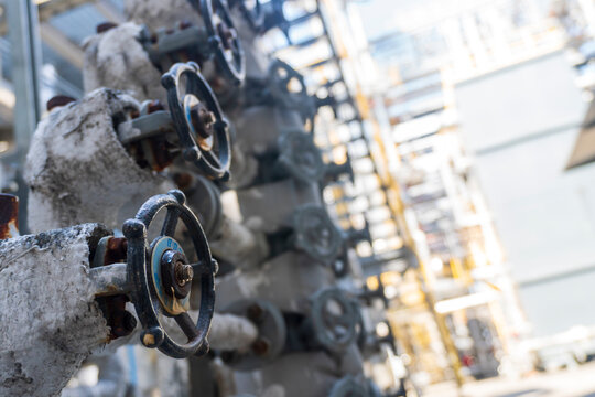 Close-up shot of industrial handwheel valves and insulated pipelines inside a chemical plant or refinery.