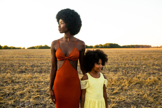 Beautiful african mom and daughter in a sunflowers field at sunset. concepts about family bond and unity, mother and child relationship, future generations, green economy, sustainable lifestyle
