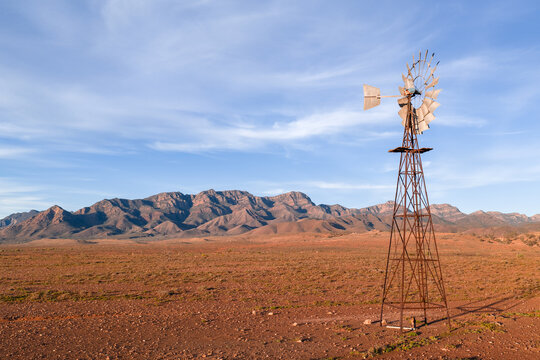 View of rustic metal windmill in an outback landscape with Heysen mountain range in background in Flinders Ranges, South Australia, Australia.