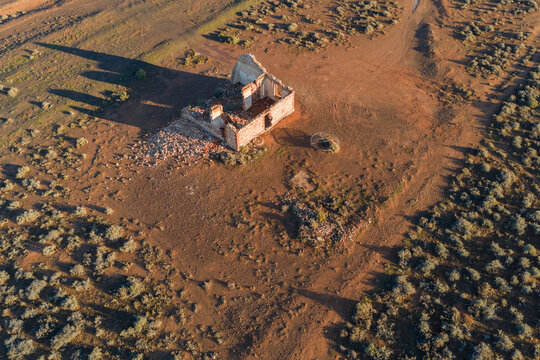 Aerial view of stone ruins of an old building in the arid desert landscape with sparse vegetation and long shadows Flinders Ranges, South Australia, Australia.