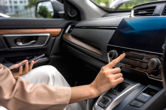 Close up unknown woman's hand selecting a music station on the car stereo dashboard player, enjoying her road trip journey
