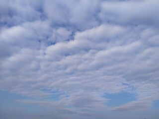 Obraz premium Beautiful blue sky filled with fluffy white cumulus clouds creating serene and peaceful natural atmosphere during bright daytime. Ideal weather and open landscape scene.