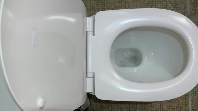 Flushing action of flush toilet bowl with water, close-up