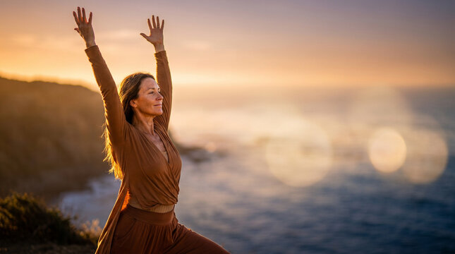 Woman doing sun salutation yoga pose at sunset on a cliffside overlooking the ocean, warm golden light, serene atmosphere, with blurred bokeh foreground