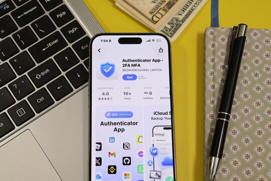 Kiel, Germany - 05-20-2026: Smartphone displaying the Authenticator App - 2FA MFA two-factor and multi-factor authentication security app in the App Store in a workspace environment with laptop and no