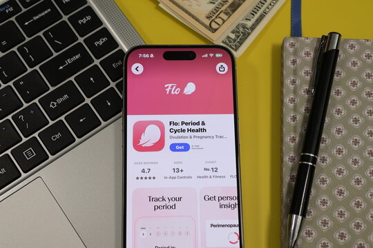 Kiel, Germany - 05-20-2026: Smartphone displaying the Flo: Period & Cycle Health menstrual cycle tracking and women&rsquo;s health app in the App Store in a workspace environment with laptop and notebook