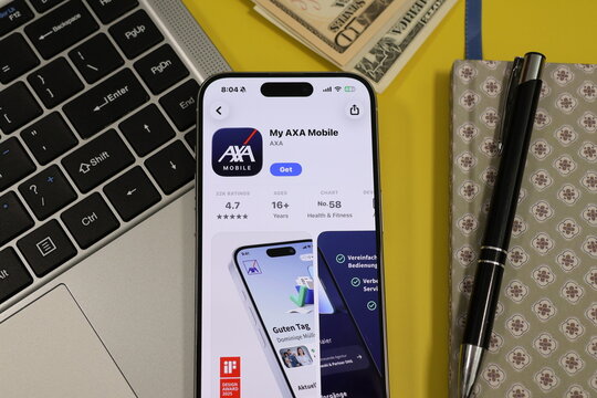 Kiel, Germany - 05-20-2026: Smartphone displaying the My AXA Mobile insurance management and customer service app in the App Store in a workspace environment with laptop and notebook