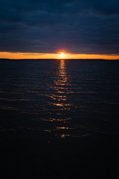 Sunset on the lake. Evening sky with beautiful clouds is reflected in the water of the lake
