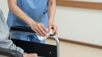 Obraz premium Female Caregiver Cleaning Wheelchair Armrest in Elderly Care Facility, Copy space on the right
