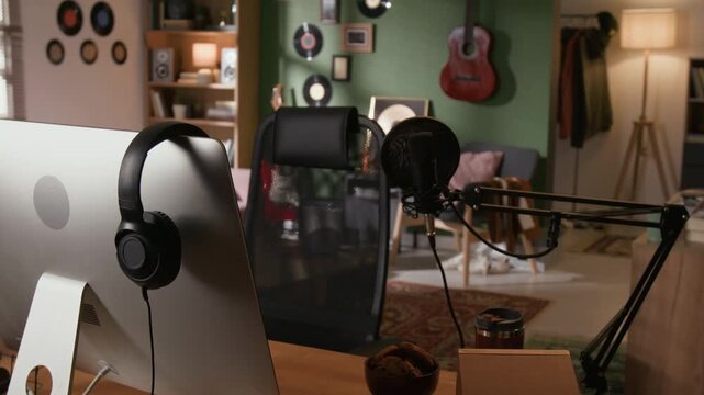 B roll shot of music production setup featuring computer monitor, professional microphone, headphones in home recording studio