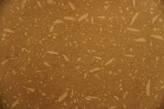 Close-up view of a brown particle board or composite wood material featuring light fiber speckles and a textured surface