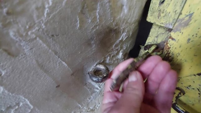 Hand opening an old rusty metal latch hook on a weathered yellow wooden door