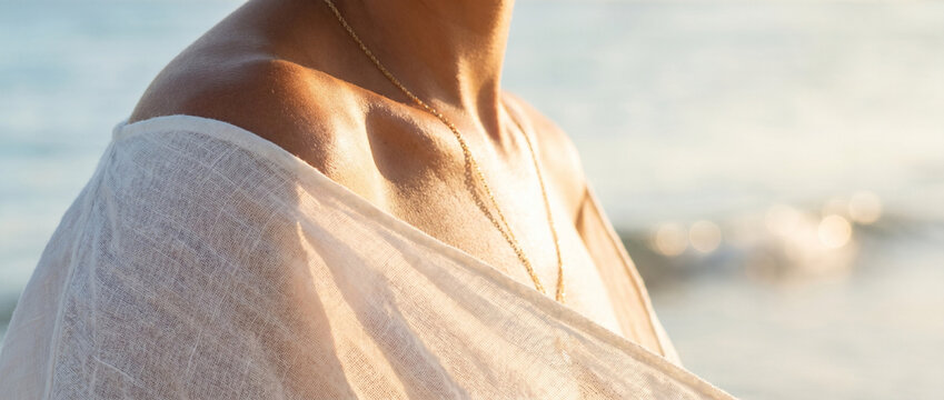 Woman with bare shoulders wearing a light shawl by the ocean  