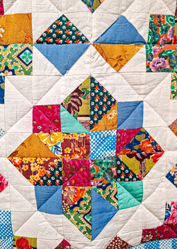 Colorful handmade patchwork quilt with floral and geometric patterns in a star design created in a bright, vibrant style