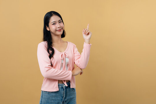 Young Asian woman pointing finger to side, presenting space